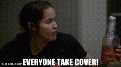 Woman In Black Shirt Holding Bottle Saying Everyone Take Cover GIF