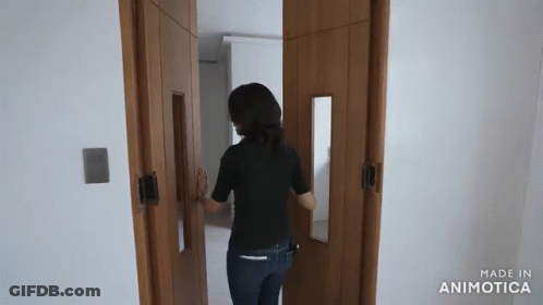 Woman In Black Shirt Walking Through Door GIF