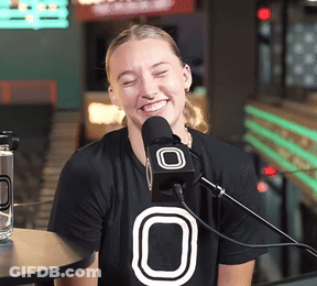 Woman In Black Shirt With O Smiling At Microphone GIF