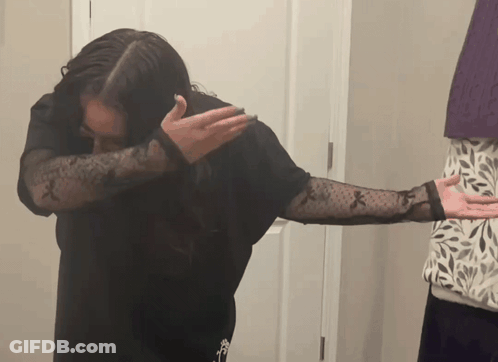 Woman In Black Shirt With Sheer Sleeves Covering Face GIF