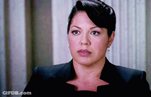 Woman In Black Suit And Earrings Looks At Camera GIF