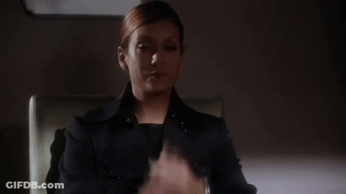 Woman In Black Suit Sitting With Hands Up GIF