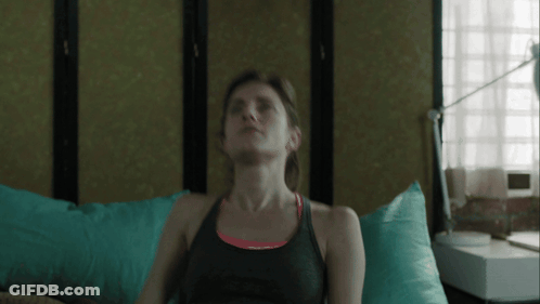 Woman In Black Tank Top Sitting On Bed Eyes Closed GIF