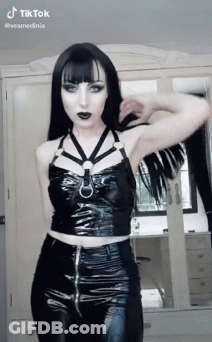 Woman In Black Top And Pants Standing In Front Of Mirror GIF