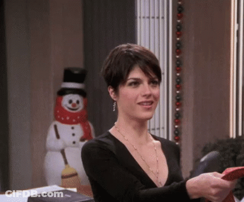 Woman In Black Top Standing By Snowman With Broom GIF