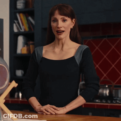 Woman In Black Top Standing In Kitchen With Hands Folded GIF