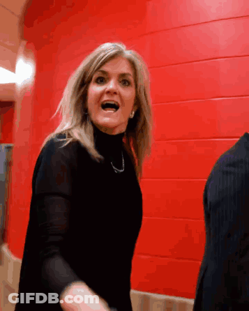 Woman In Black Turtleneck Screaming Before Red Wall GIF