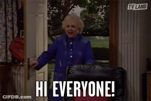 Woman In Blue Coat Standing In Doorway Says Hi Everyone GIF