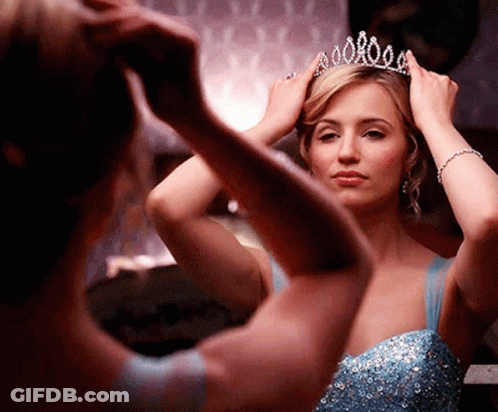 Woman In Blue Dress Adjusting Tiara In Mirror GIF