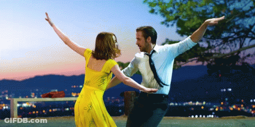 Woman In Blue Dress And Necklace Looking At Camera GIF
