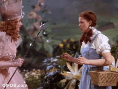 Woman In Blue Dress Beside Woman In Pink Dress With Wand GIF