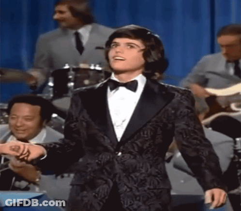 Woman In Blue Dress Holding Glass Asks About Love Spell GIF