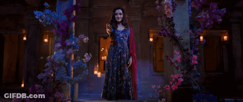 Woman In Blue Dress In Front Of Flowers GIF