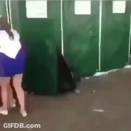 Woman In Blue Dress In Front Of Green Stalls GIF