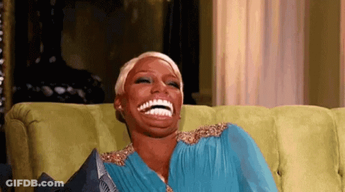 Woman In Blue Dress Laughing On Green Couch GIF