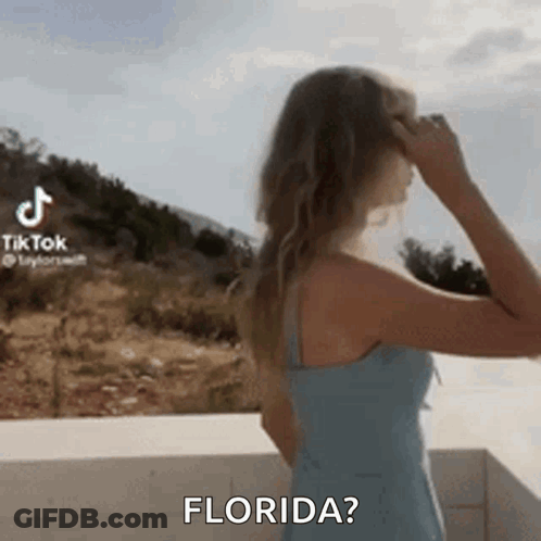 Woman In Blue Dress On Balcony Hand In Hair Asking Florida GIF