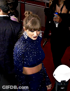 Woman In Blue Dress On Red Carpet With Man In Striped Sweater GIF