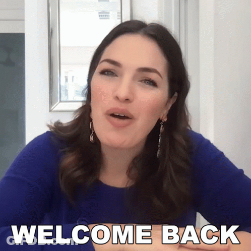 Woman In Blue Dress Saying Welcome Back GIF