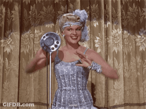 Woman In Blue Dress Smiling At Microphone GIF