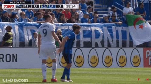 Woman In Blue Dress Touching Belly In Crowd GIF