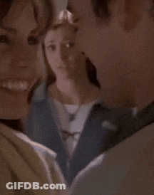 Woman In Blue Jacket And Glasses Standing In Front Of Bookshelf GIF