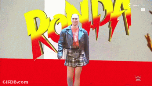 Woman In Blue Jacket And Plaid Skirt In Front Of Ronda Sign GIF