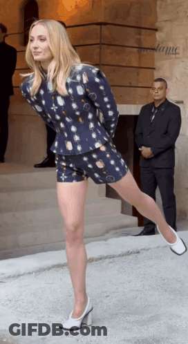 Woman In Blue Jacket And Shorts Standing With One Leg Up GIF