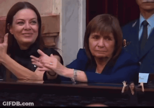 Woman In Blue Jacket Beside Woman In Black Dress GIF