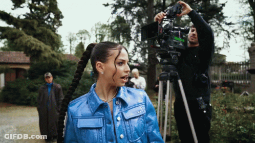 Woman In Blue Jacket In Front Of Cameraman GIF