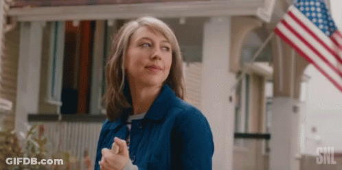 Woman In Blue Jacket In Front Of House With American Flag GIF