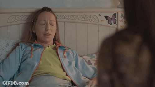 Woman In Blue Jacket Laying On Bed With Butterflies GIF