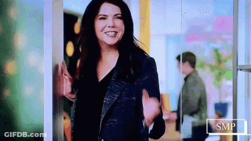 Woman In Blue Jacket Smiling And Waving GIF