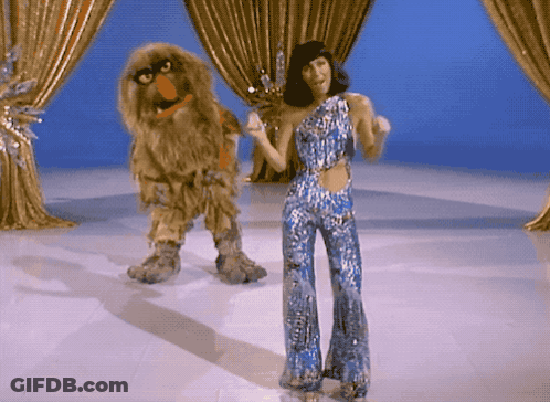 Woman In Blue Jumpsuit Dancing Next To Sesame Street Character GIF