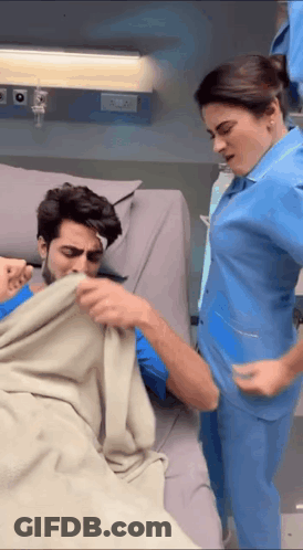 Woman In Blue Scrub And Man In Hospital Bed GIF