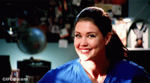 Woman In Blue Scrub Top Smiling In Front Of Globe GIF