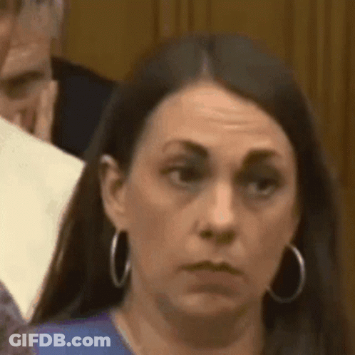 Woman In Blue Shirt And Hoop Earrings Looking Serious GIF