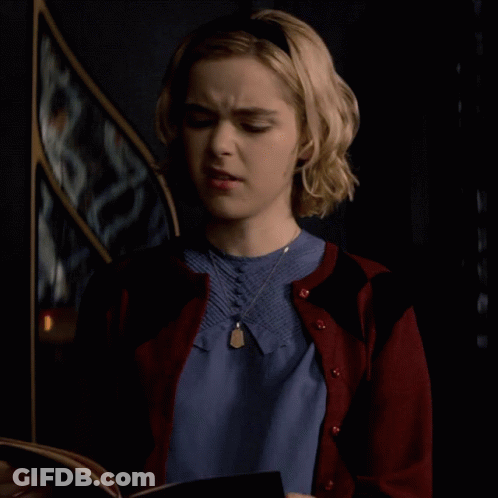 Woman In Blue Shirt And Red Cardigan Looking At Book GIF