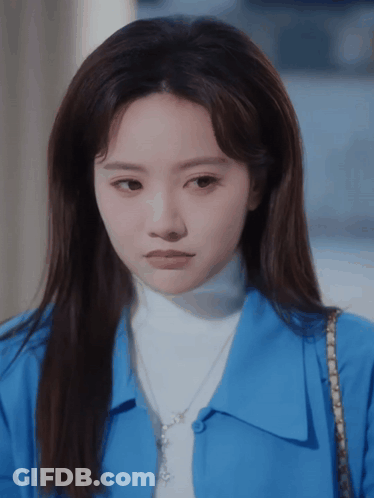 Woman In Blue Shirt And White Turtleneck Looking At Camera GIF