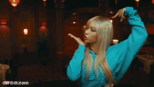 Woman In Blue Shirt Dancing In Front Of Red Wall With Lanterns GIF