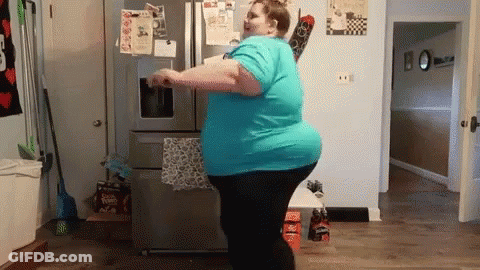 Woman In Blue Shirt Dancing In Front Of Refrigerator GIF