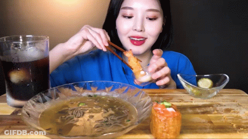 Woman In Blue Shirt Eating Fried Food With Chopsticks GIF