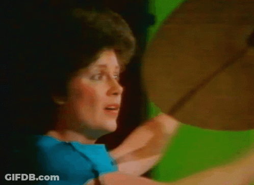 Woman In Blue Shirt Holding Cymbal GIF