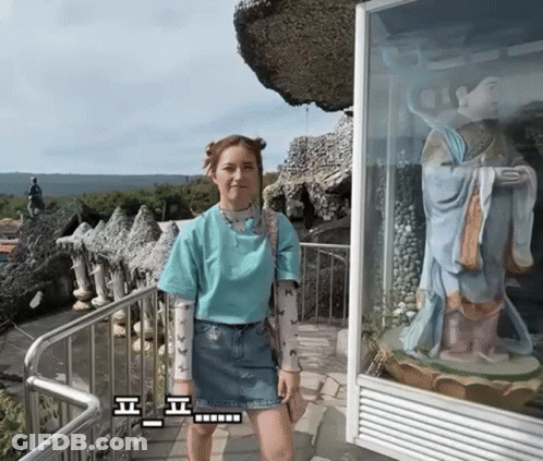Woman In Blue Shirt In Front Of Statue GIF