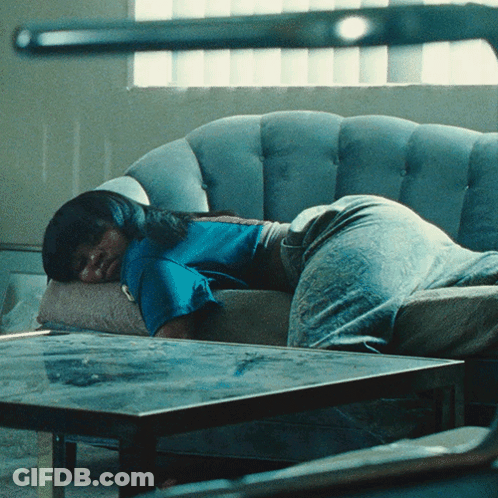 Woman In Blue Shirt Laying On Grey Couch GIF