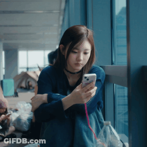 Woman In Blue Shirt Looking At Cell Phone GIF