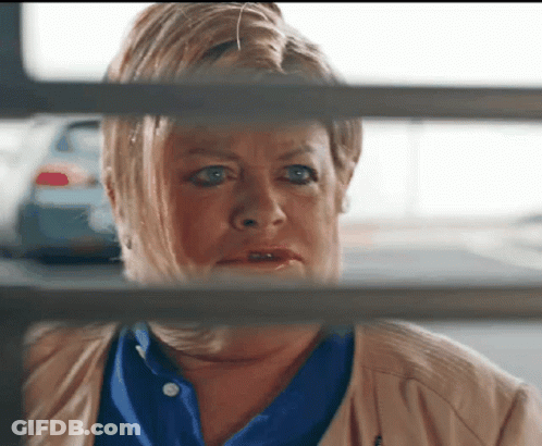 Woman In Blue Shirt Looking Through Fence GIF