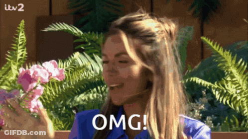 Woman In Blue Shirt Saying OMG With Flowers And Ferns GIF