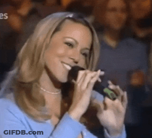 Woman In Blue Shirt Singing Into Microphone In Front Of Crowd GIF