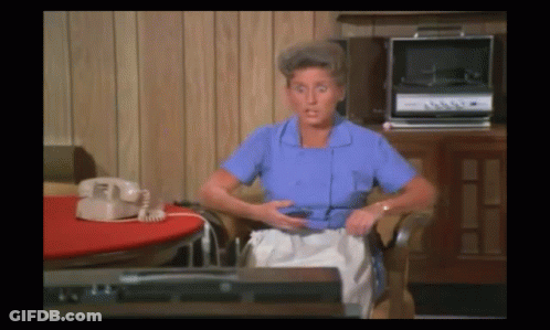 Woman In Blue Shirt Sitting By Record Player And Telephone GIF