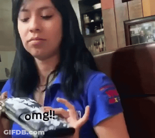 Woman In Blue Shirt Sitting In Booth Holding Cell Phone GIF